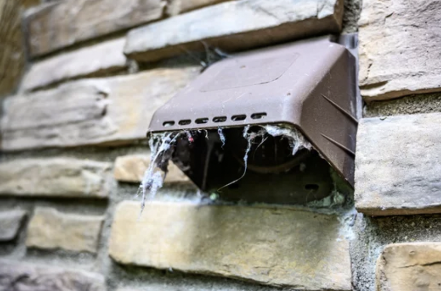 an exterior part of a garage dryer vent which is covered with lint and needs cleaning as it is a fire hazard